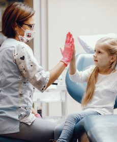 Cute little girl sitting in the dentist's office Little girl talking to the dendist. Child in the dentist's office. Woman in a uniform